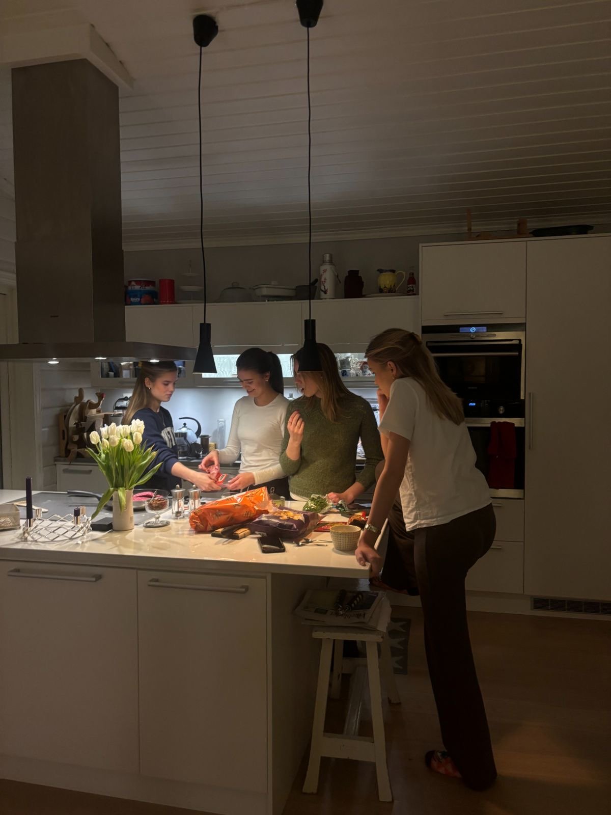 A group of women gathered around a kitchen island together, cooking and laughing.