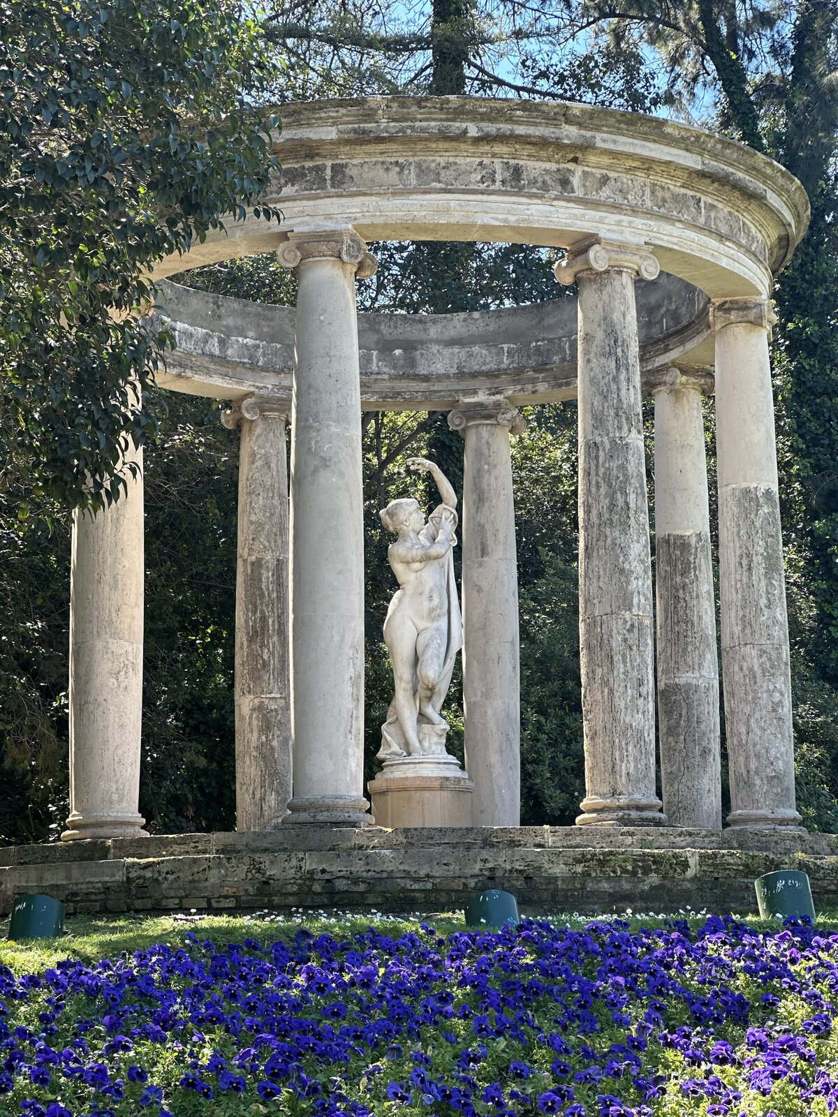 A neoclassical garden pavilion with statue and flowerbeds in the botanical gardens of Montjuïc, Barcelona.