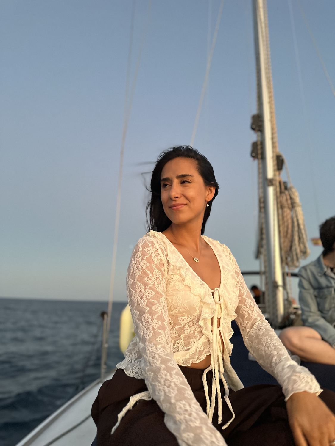 Close portrait of a woman in a lace top on a sailboat at golden hour.