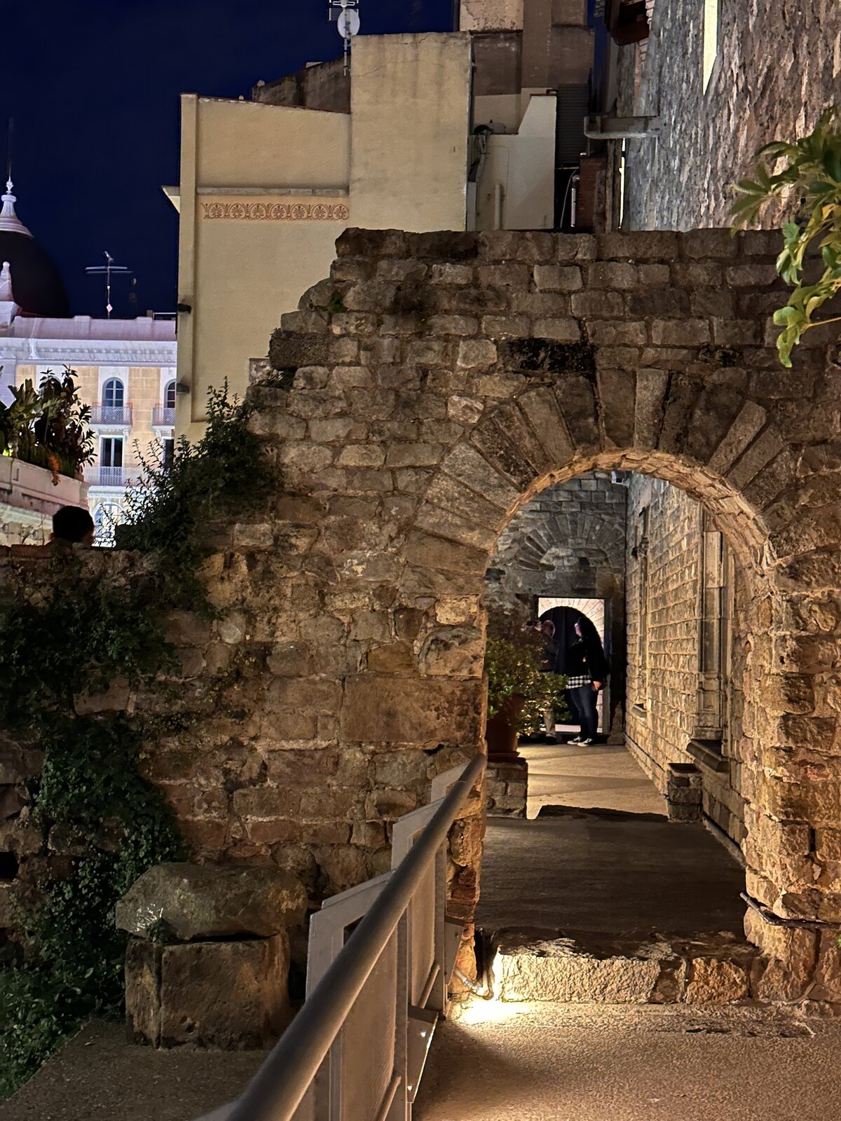 A narrow stone archway alley lit up at night in a Catalan old town.